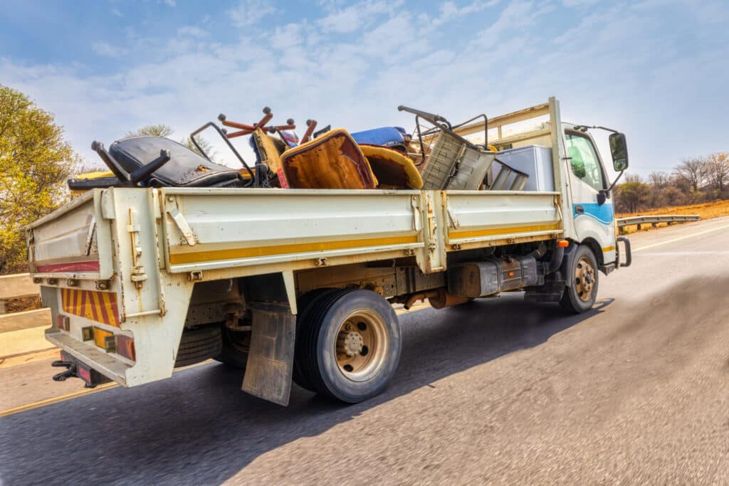 Large truck on the city street, carry used broken household items.