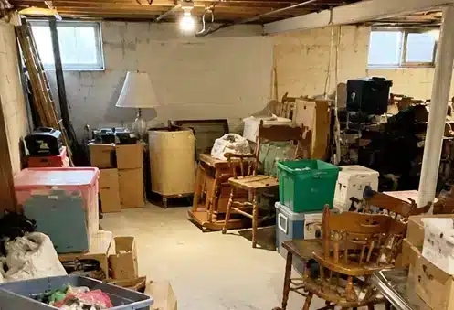 Cluttered basement filled with furniture, boxes, bins, and household items