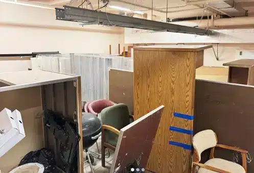 Office filled with cubicles, cabinets, chairs, and unwanted furniture