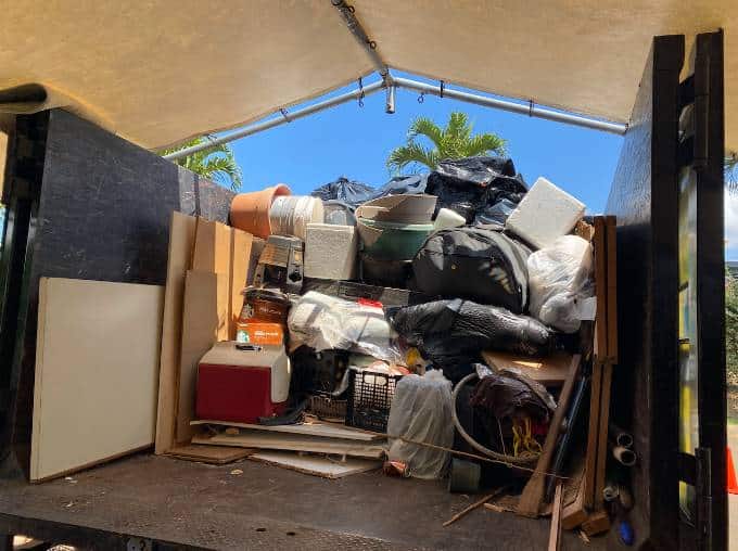 Junk removal truck loaded with household waste, bags, furniture, and containers