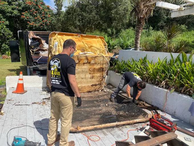 Junk removal team dismantling an old hot tub at a residential property